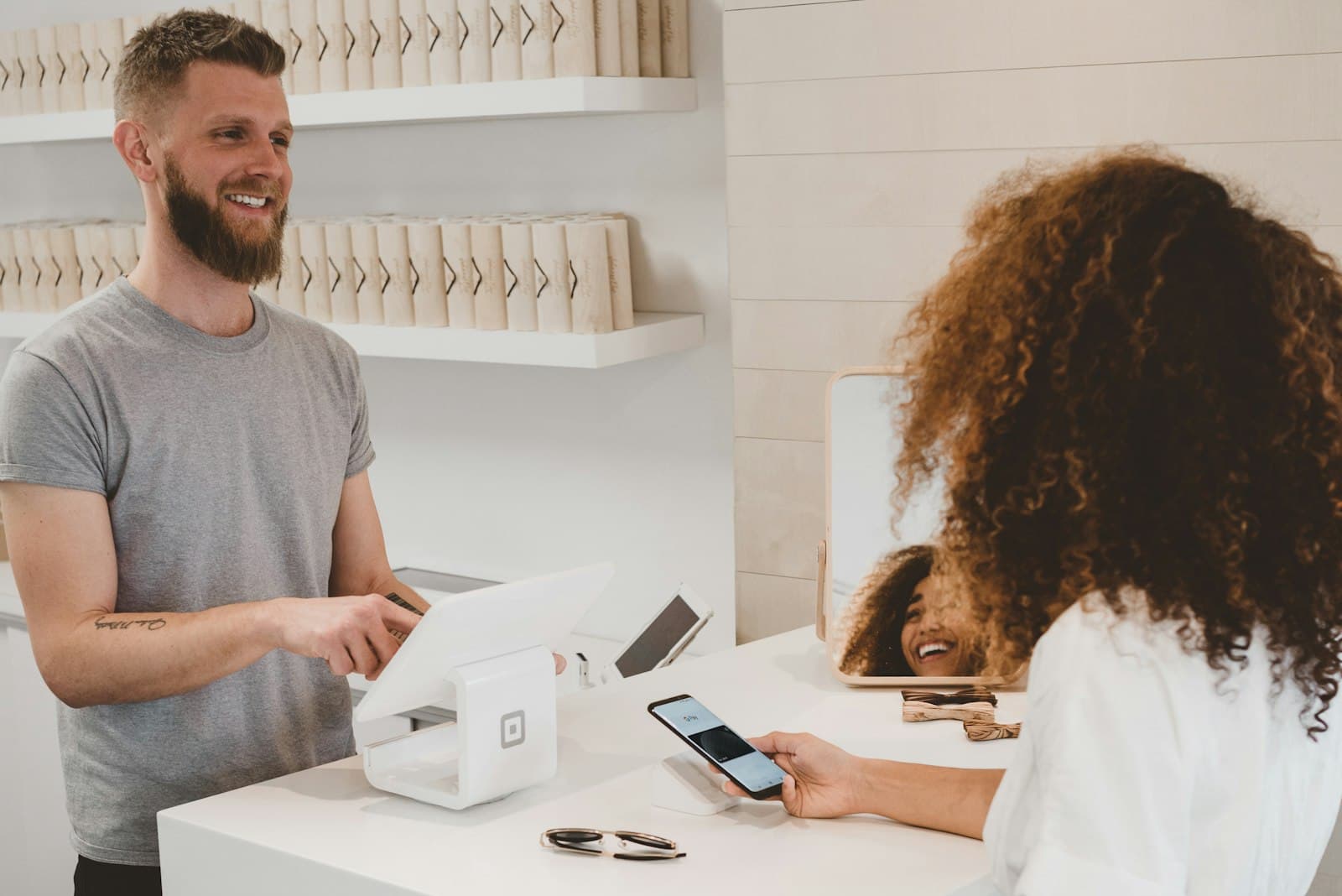 Dueño de un comercio cobrándole a una clienta que paga con el celular